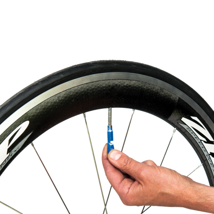 anodised blue Park Tool VC-1 Valve Core Tool being used to remove a presta valve core from a ZIPP 404.