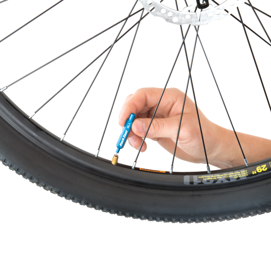 anodised blue Park Tool VC-1 Valve Core Tool being used to remove a schrader valve core from a WTB wheel.