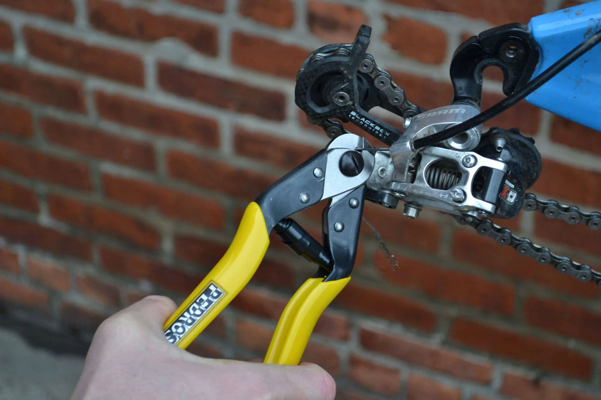 Pedro's cable cutter being used to cut bicycle shift inner cable near the rear derailleur