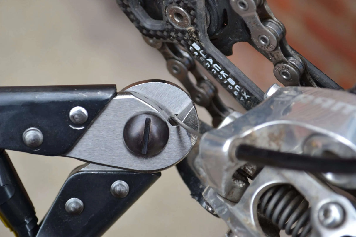 close up of Pedro's cable cutter being used to cut bicycle shift inner cable near the rear derailleur