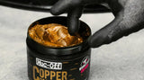 Muc Off Copper Paste being picked out of tub using a gloved-finger
