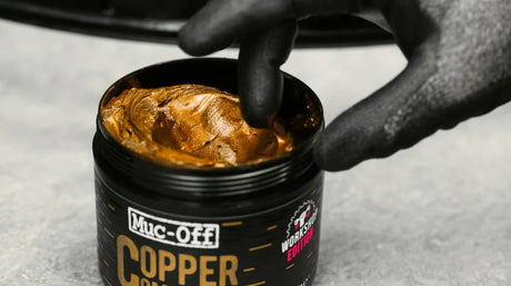 Muc Off Copper Paste being picked out of tub using a gloved-finger