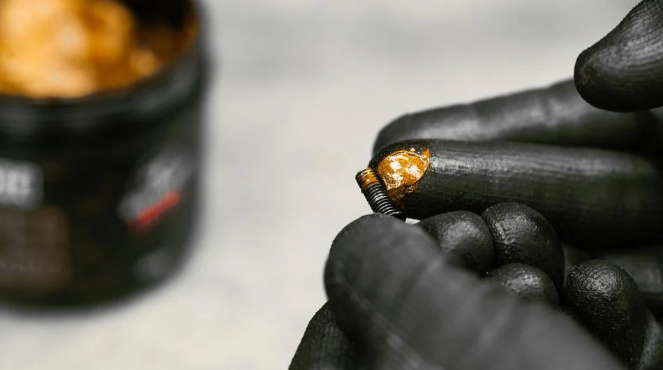Muc Off Copper Paste being applied to a small m5 bolt using a gloved finger