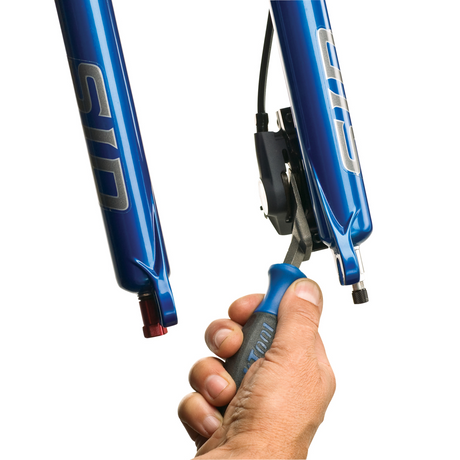 Park Tool PP-1 being used to spread pistons on an XTR m970 disc brake caliper mounted to a blue SID fork